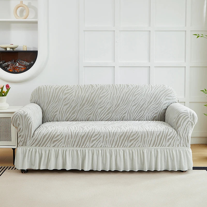 A light gray sofa cover featuring a zebra stripe pattern and an elastic skirt displayed indoors.