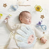 A baby is sleeping peacefully on a white blanket with a soothing palm-shaped silicone hand pillow.
