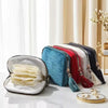 A collection of velvet jewelry organizer bags in various colors like blue, red, and black with tassels displayed on a white m