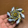 A metal fidget spinner with silver and gold components is held in a hand against a brown leather background.