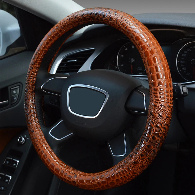 A close-up view of a brown crocodile grain leather car steering wheel cover.