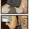 A person holds a black and white crystal-embellished chain shoulder bag with a gold-yellow top.