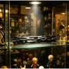 A black willow wood wishing stick displayed on a glass shelf among collectible figures.