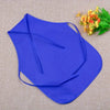 A royal blue non-woven fabric craft apron is displayed on a beige cloth next to some yellow and green flowers.