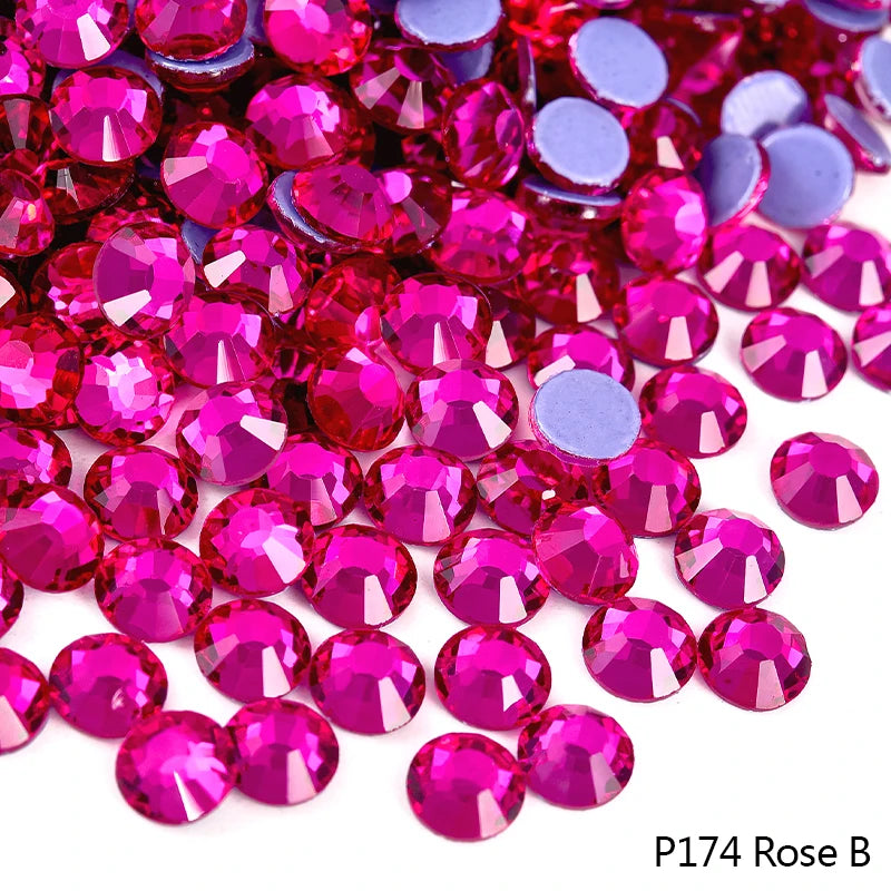 A close-up of pink and purple faceted rhinestones scattered on a white background.