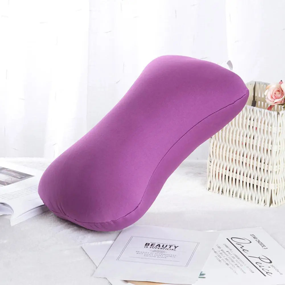 A purple microbead bolster pillow is shown resting on a white surface next to a woven basket and some papers.