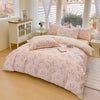 A pink floral printed duvet cover set with pillows displayed on a bed in a bright room.
