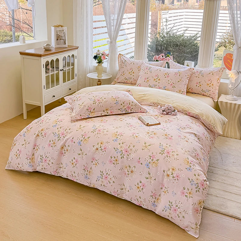 A pink floral printed duvet cover set with pillows displayed on a bed in a bright room.