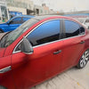 A close-up view of a red car with dark tinted windows and a black roof, showing the side profile.