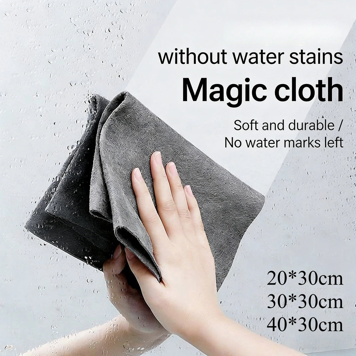 A hand is wiping a glass with a gray microfiber cloth, demonstrating the streak-free cleaning ability of the magic cloth.