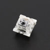 A close-up view of a white mechanical keyboard switch housing with a black cross-shaped component.