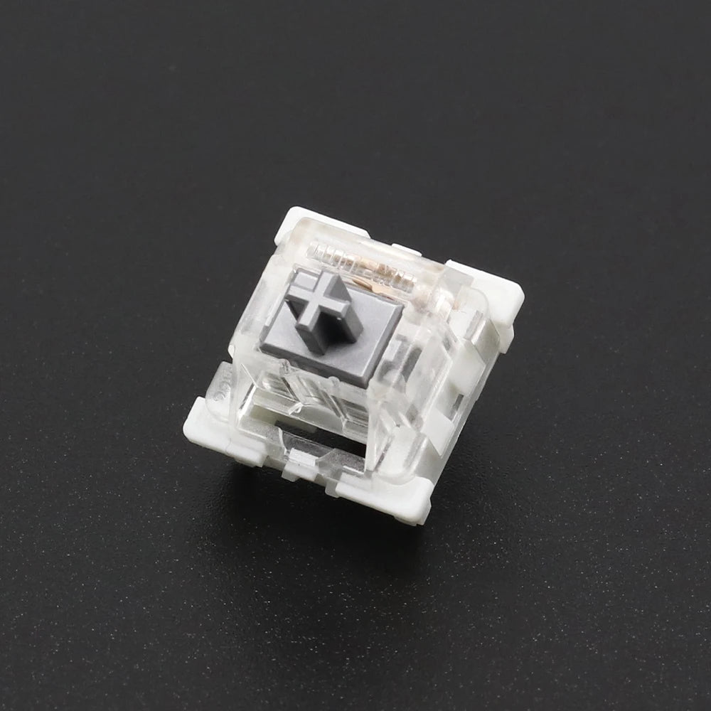 A close-up view of a white mechanical keyboard switch housing with a black cross-shaped component.