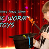 A young child dressed as a wizard holds an orange worm magic trick prop against a red curtain background.