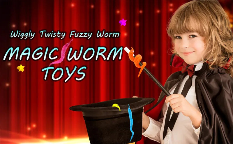 A young child dressed as a wizard holds an orange worm magic trick prop against a red curtain background.