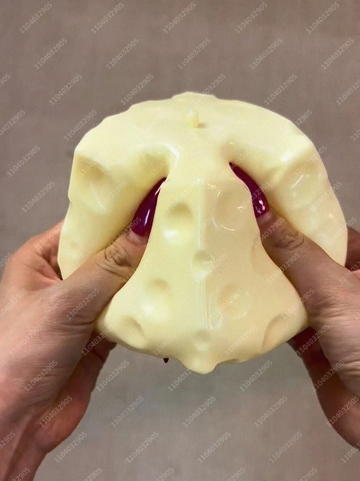 Eine Hand drückt einen großen, blassgelben, unregelmäßig geformten Stressball.