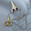 Vintage stainless steel sewing scissors with a chain attached