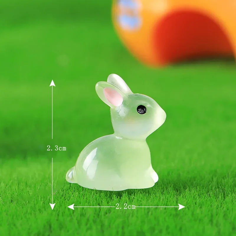 A small, translucent pale green resin miniature bunny figurine sitting on bright green grass.
