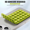 A green silicone suction cup pad with multiple circular indentations is shown placed on a silver phone mount.