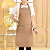 A person wearing a beige cotton apron in a light-colored shirt standing in a well-lit room.