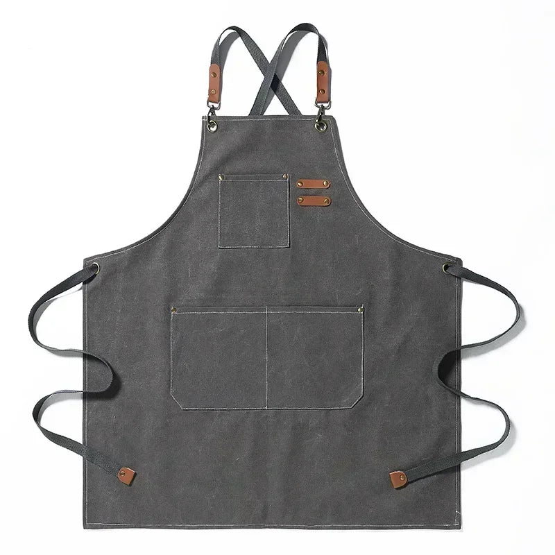A dark gray cotton canvas apron with cross-back straps and multiple pockets.