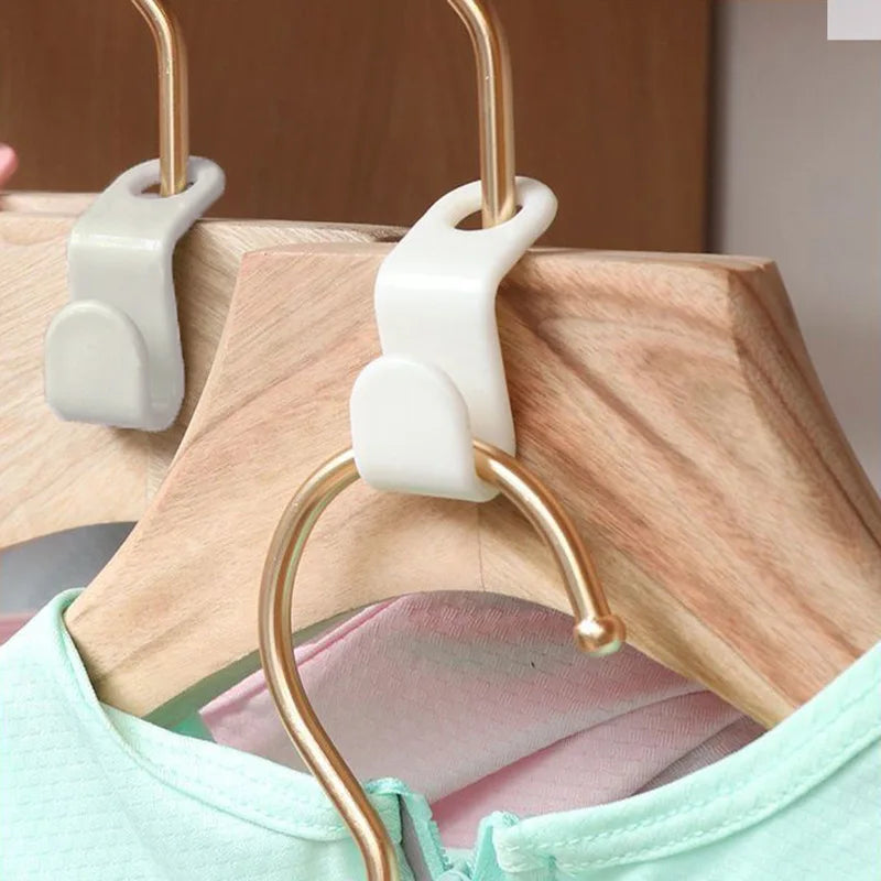 Gold and white plastic hanger connectors hanging on a wooden hanger above a light green shirt.