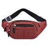 A maroon canvas waist pack with a black strap and zippered pockets shown from above.