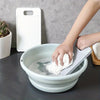A hand is using a white non-slip laundry scrubbing board to clean a bowl of water.