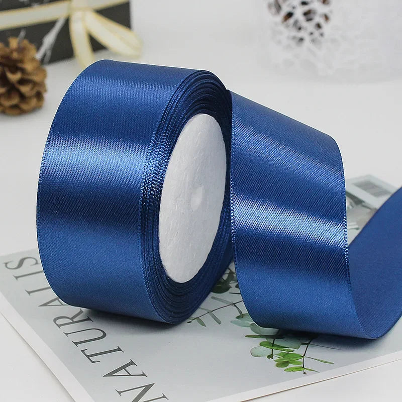 A roll of deep blue satin ribbon used for gift wrapping or DIY crafts.