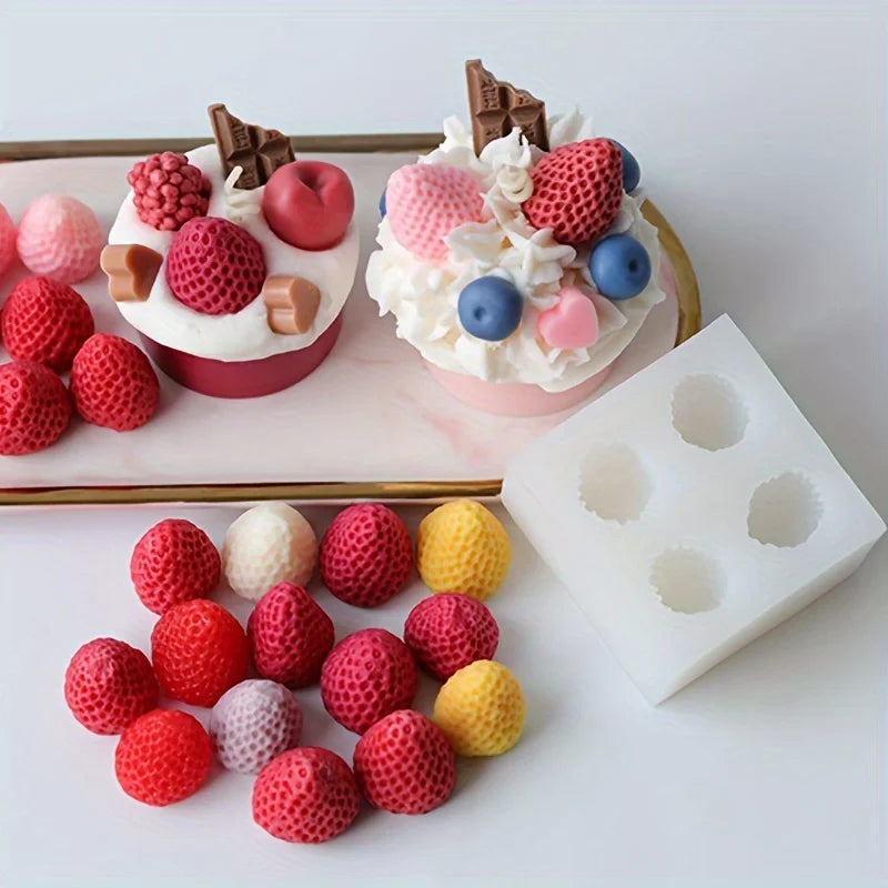 Présentation de moules en silicone en forme de fraise rouge et rose pour cire de bougie DIY, sur un plateau blanc.