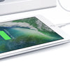 A tablet screen displaying a vibrant green battery icon indicating 100% charged, next to a white charger and cable.