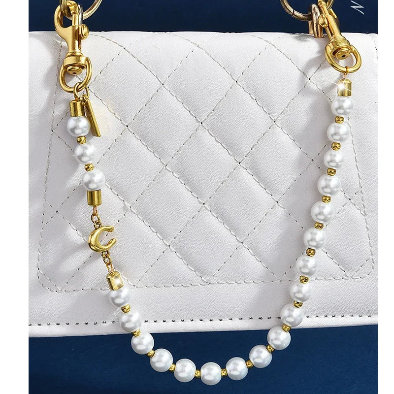 Gold and pearl necklace with a letter C charm displayed against a white quilted purse.
