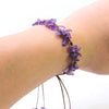 A bracelet made of purple amethyst quartz chips is braided onto a person's wrist.
