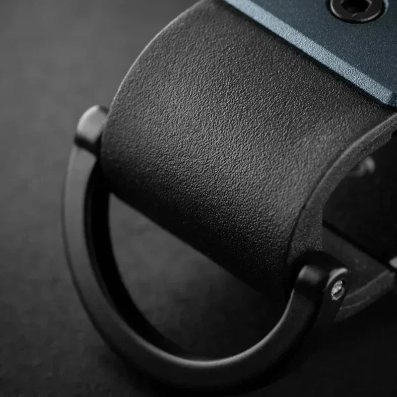 A close-up view of a black minimalist aluminum key organizer with a textured grip and a circular opening.
