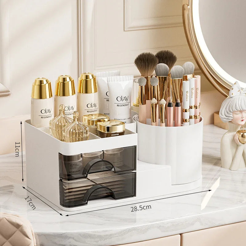 A white desk organizer with transparent drawers holds various makeup brushes and cosmetic products.