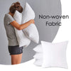 A woman is hugging a large white cushion against a gray wall, with another white cushion visible in the foreground.