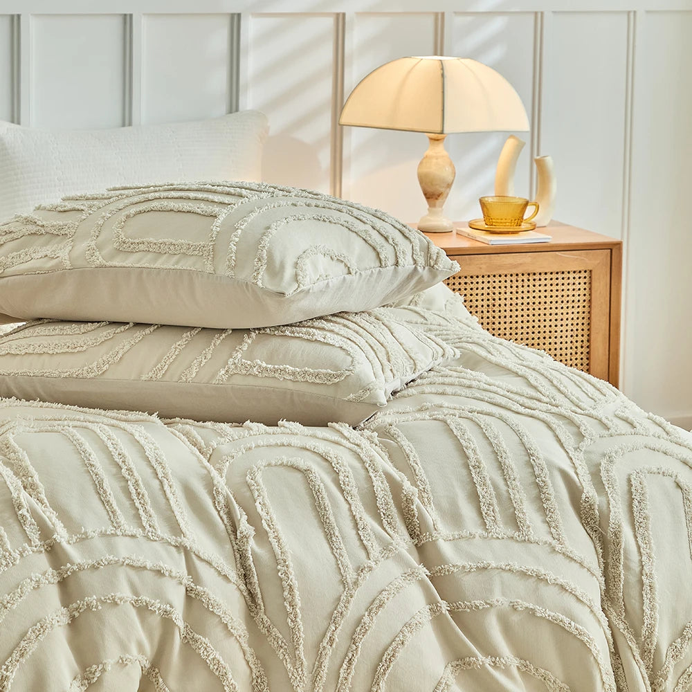 Beige, geprägte Blumen-Decke für Bett mit Lampe und goldener Tasse.