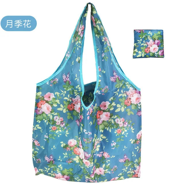 A light blue floral nylon reusable shopping tote bag with pink and green flowers.