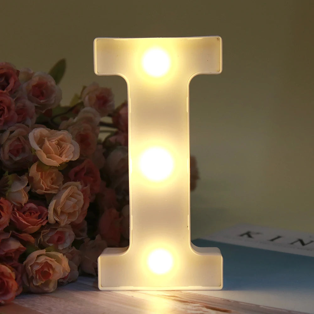 Lumière nocturne en forme de lettre I, alphabet blanc LED lumineux, posée sur une surface en bois.