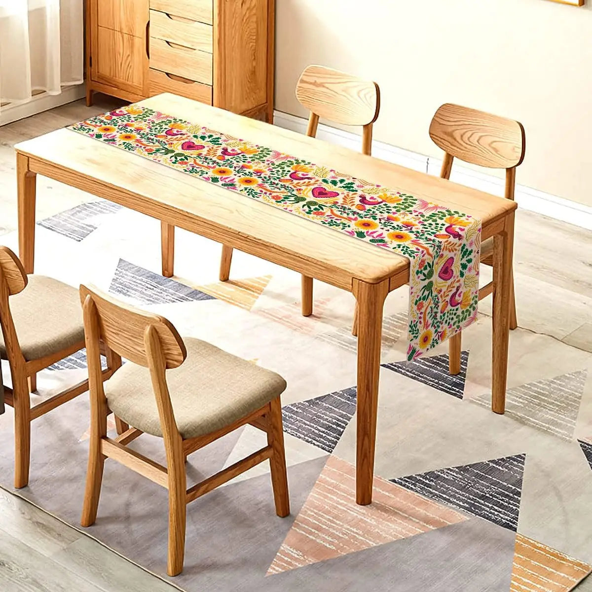 A light wood dining table set with a colorful Day of the Dead Mexican Fiesta table runner on a patterned rug.