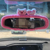 Plush bear and pig shaped covers placed on a car's rearview mirror.