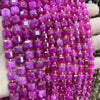 A close-up of pink and magenta square faceted beads strung together for jewelry making