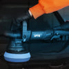 A hand wearing an orange sleeve and black glove is operating a black dual action polisher with a 15mm orbit attachment for ca