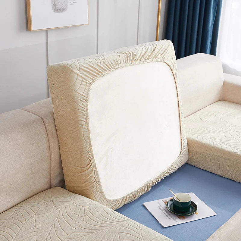 A close-up of a beige stretch jacquard sofa cover with an anti-slip backing on a light blue sofa.