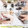 A hand is using a heavy-duty emery sponge brush to clean a metal pot or pan.