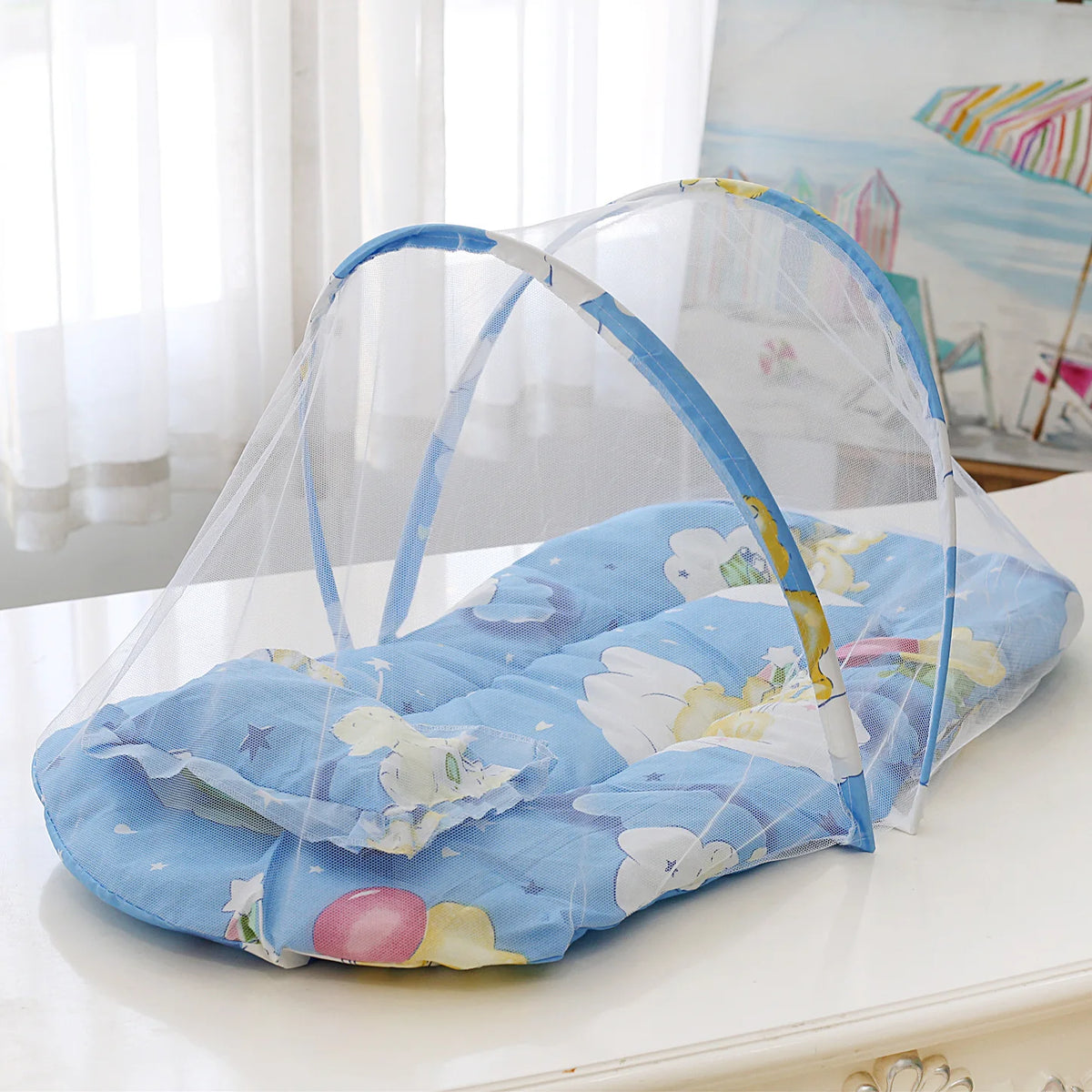 A foldable baby mosquito net is shown spread over a mattress with a pillow, ready for use.