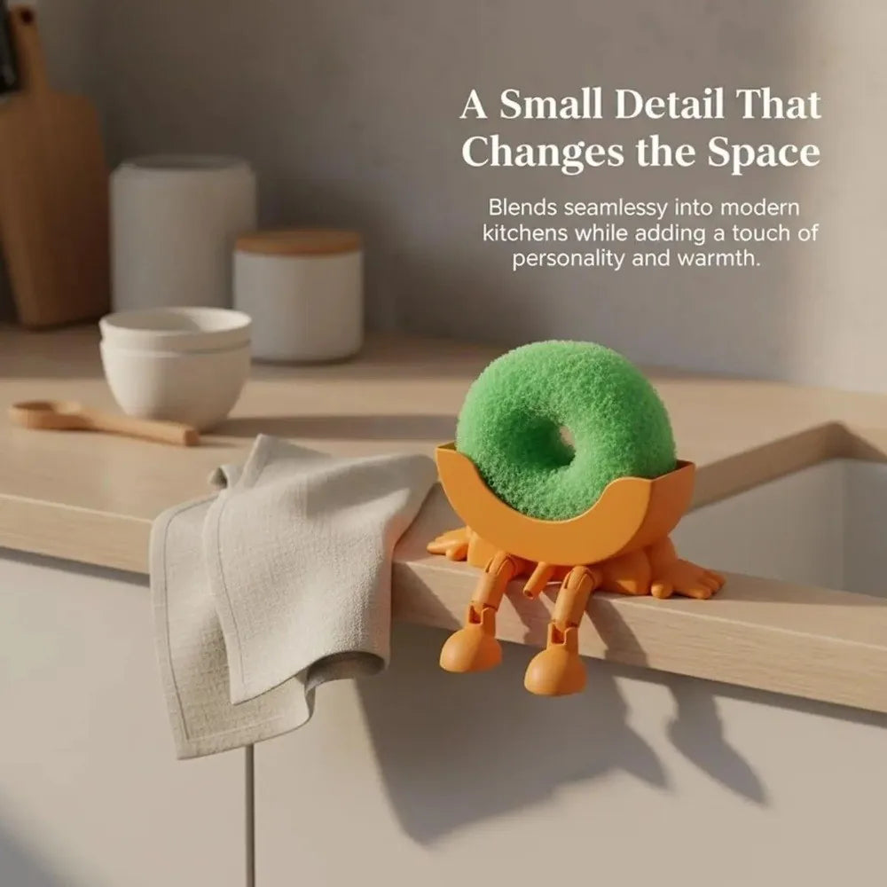 A cute 3D sponge holder with a green foam top and wooden base is shown on a kitchen counter.