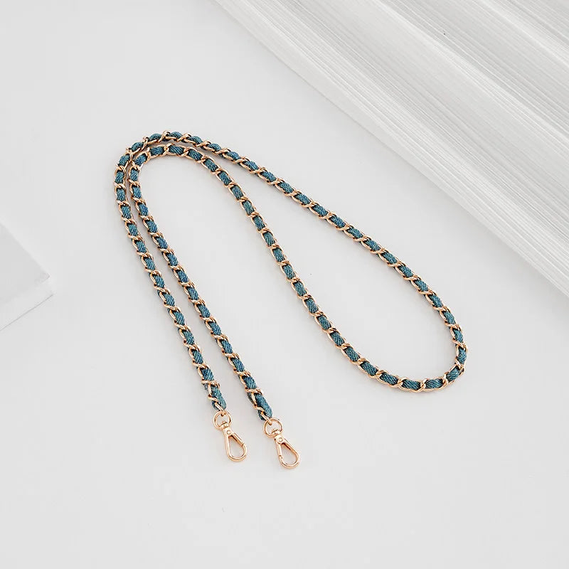 A delicate chain shoulder strap buckle in gold-toned metal and turquoise beads is displayed on a white background.