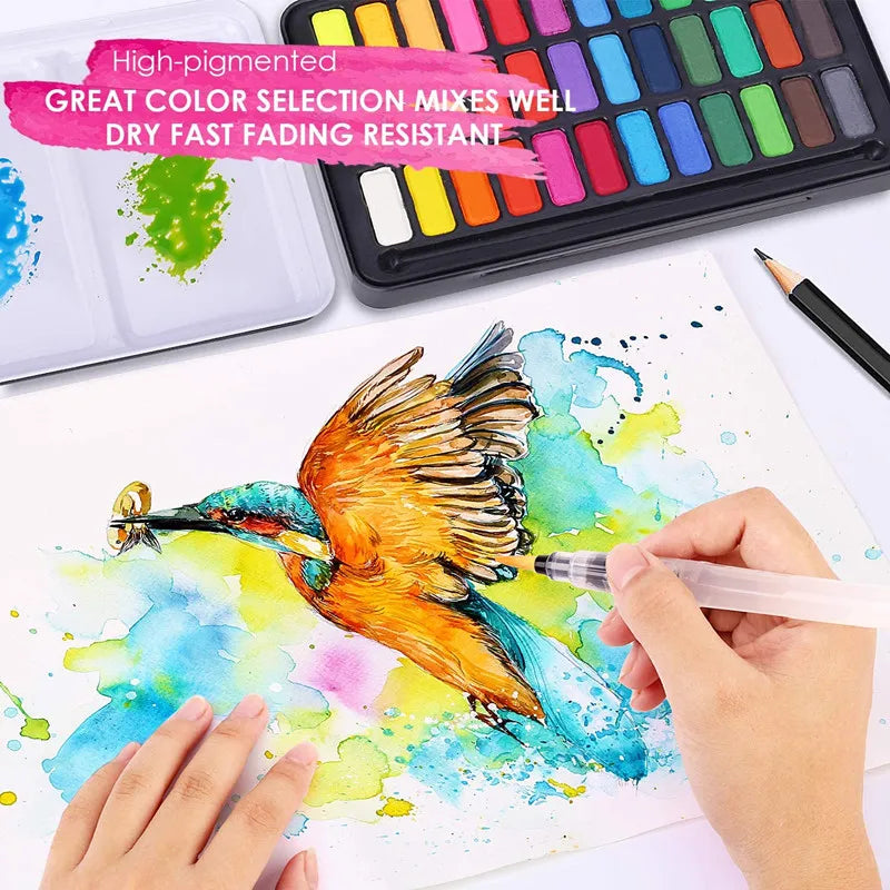 A hand paints a vibrant watercolor bird on paper using paint from a professional set with a metal case.