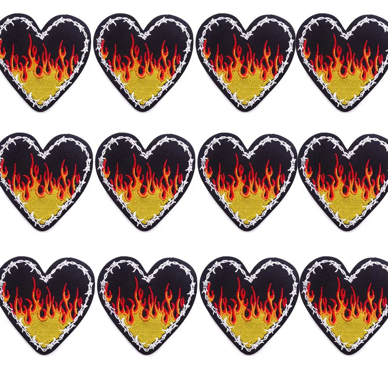 A pack of ten heart-shaped embroidered iron-on patches featuring a rock skull and flame design on black fabric with gold acce