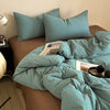A teal striped duvet cover set with matching pillows is displayed on a bed.